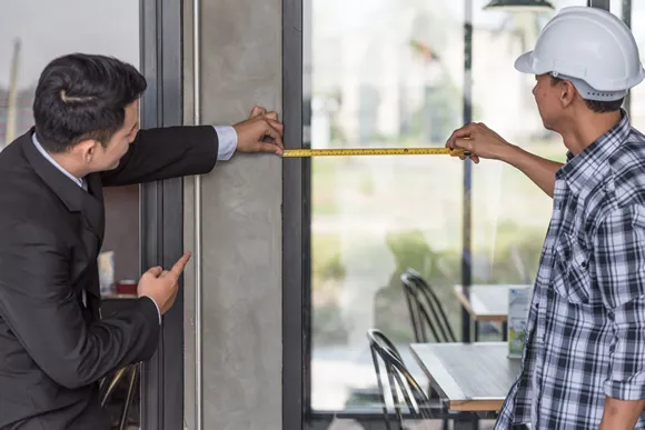 employer and foreman measuring glass window at site