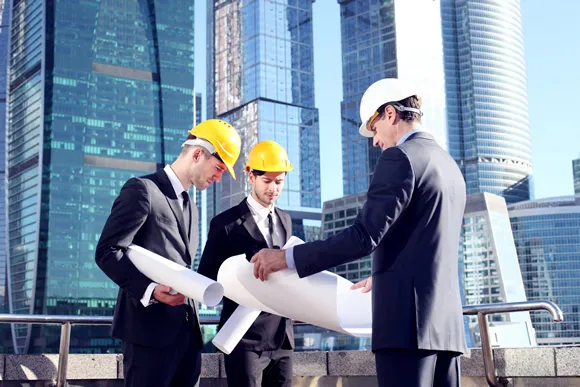 Architects with blueprint at skyscrapers background