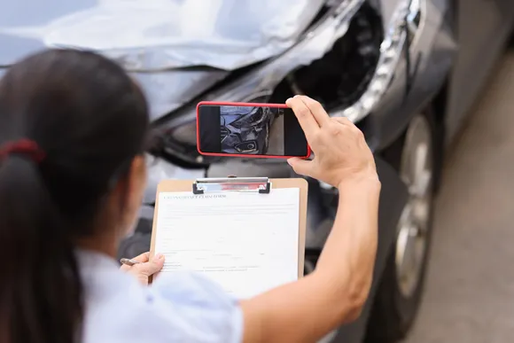 Insurance agent is filming damage to crashed car