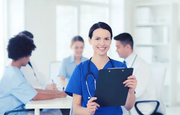 nurse with clipboard over group of medics meeting