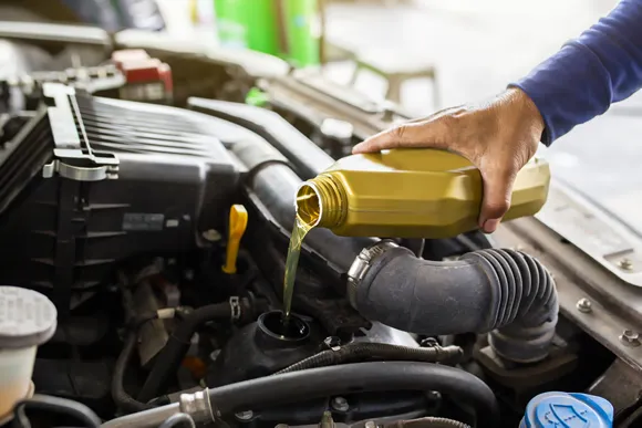 Car mechanic replacing and pouring fresh oil into engine at maintenance repair service station